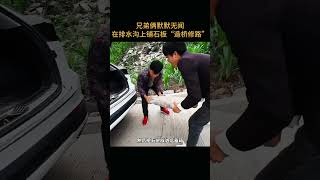 兄弟俩默默无闻，在排水沟上铺石板“造桥修路”